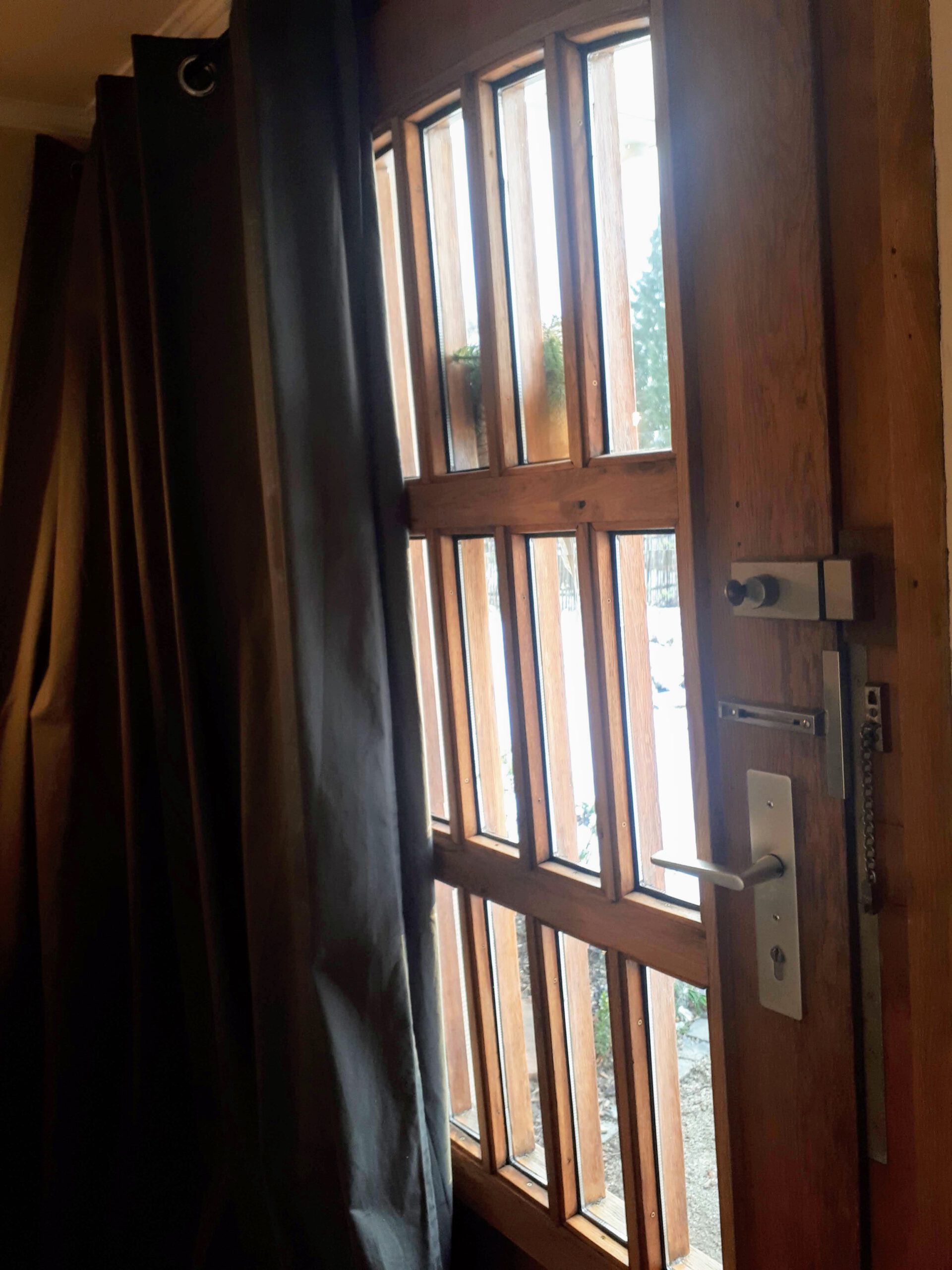 Die alte Haustür sanieren mit Doppelverglasung sowie einem schweren Vorhang.